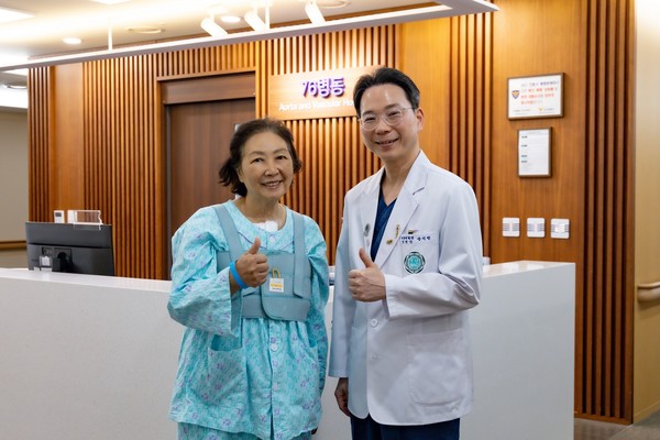 김 모 씨(여, 69세)가 급성 대동맥박리증 수술을 집도한 송석원 이대대동맥혈관병원장과 이대서울병원 76병동에서 기념촬영을 하고 있다.