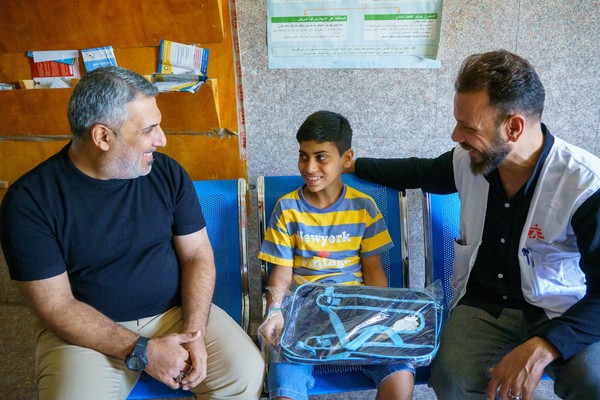 조기 결핵 진단을 받은 아동과 아버지, 국경없는의사회 직원과 함께 앉아 있다. 치료를 마친 그는 곧 학교로 돌아갈 예정이다. [제공=국경없는의사회 9월 촬영]